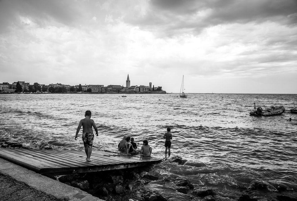 a man walking across a wooden pier next to a body of water