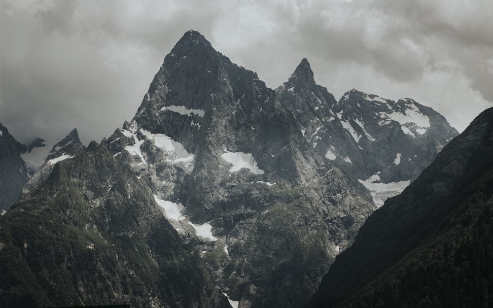 a mountain range covered in snow under a cloudy sky