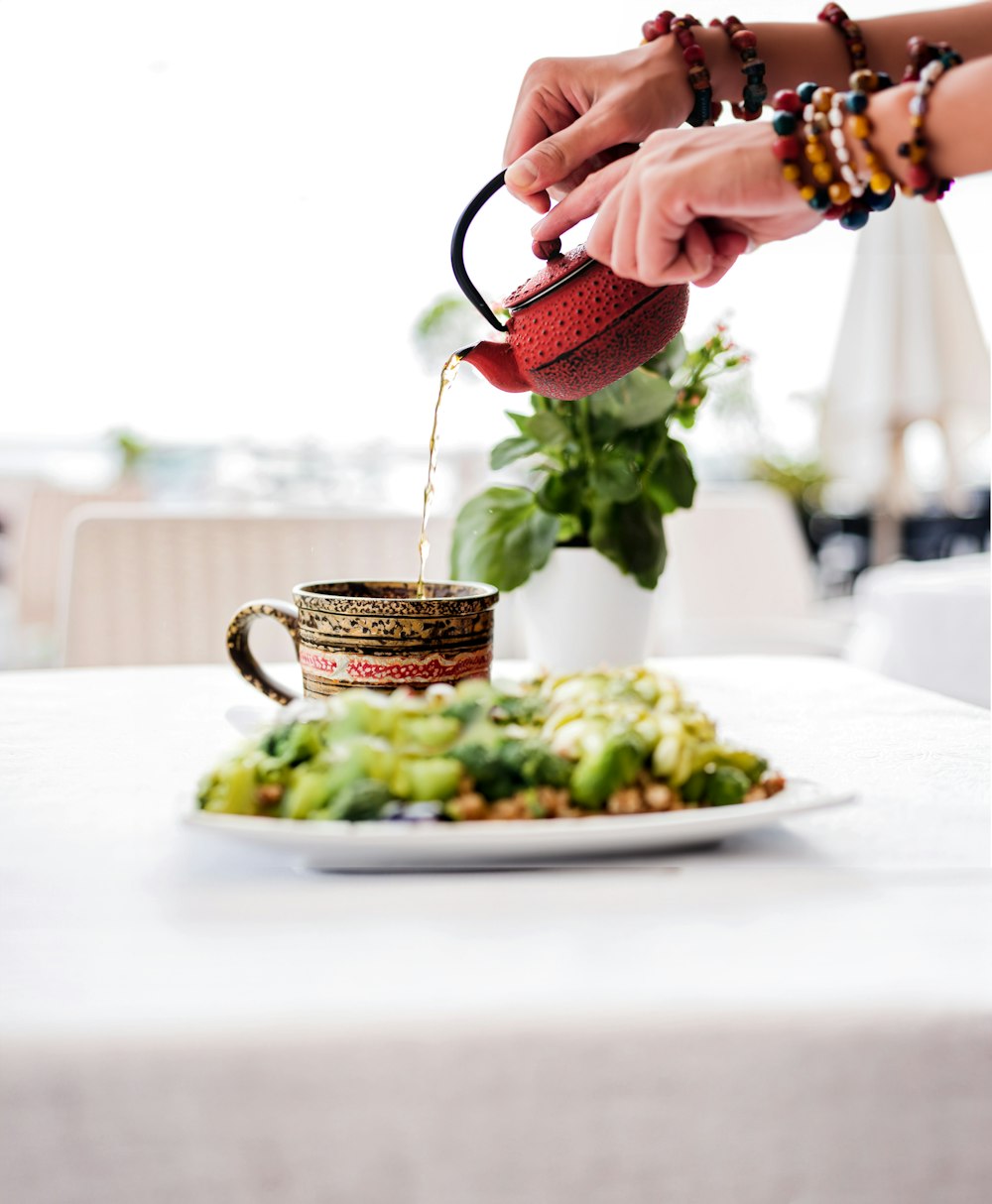 a person pouring tea into a cup on a plate