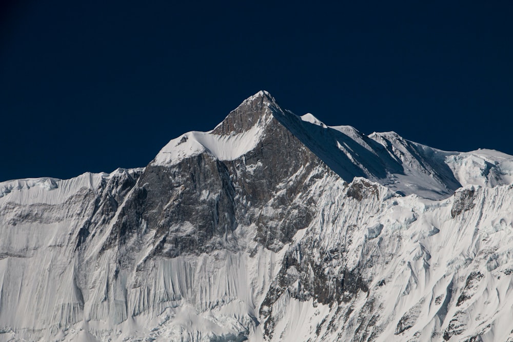 a large mountain covered in snow under a blue sky