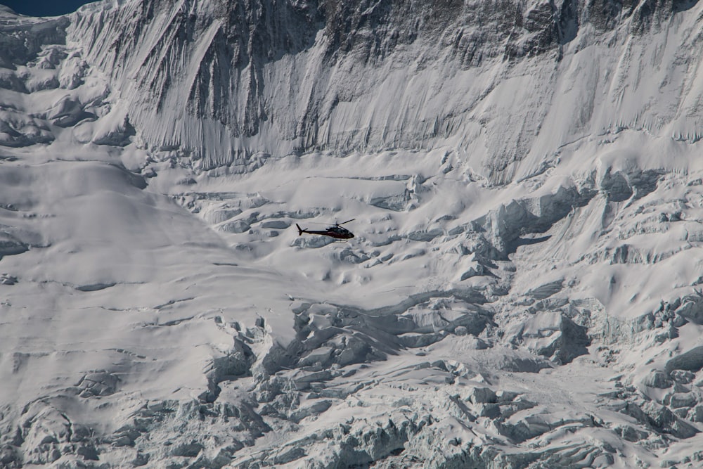 Ein Hubschrauber fliegt über einen schneebedeckten Berg