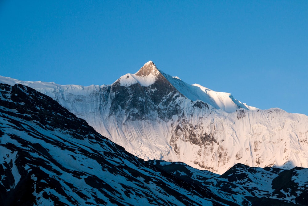 a mountain covered in snow under a blue sky