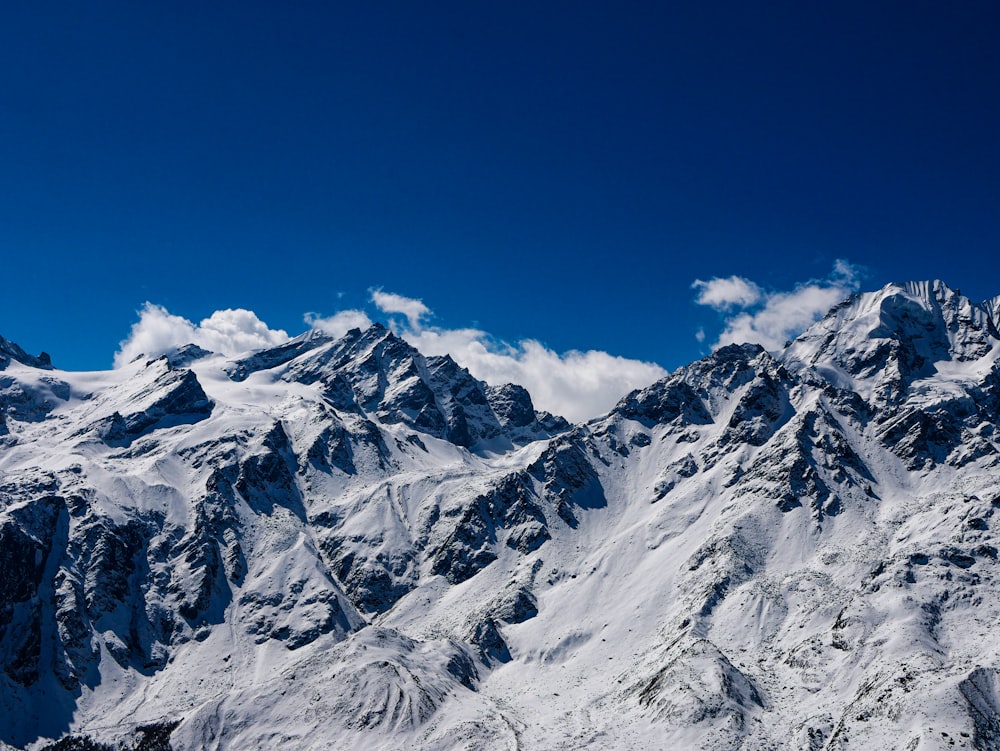 a snow covered mountain range under a blue sky