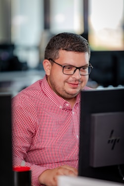 A focused professional working on a laptop surrounded by organized documents and digital screens.