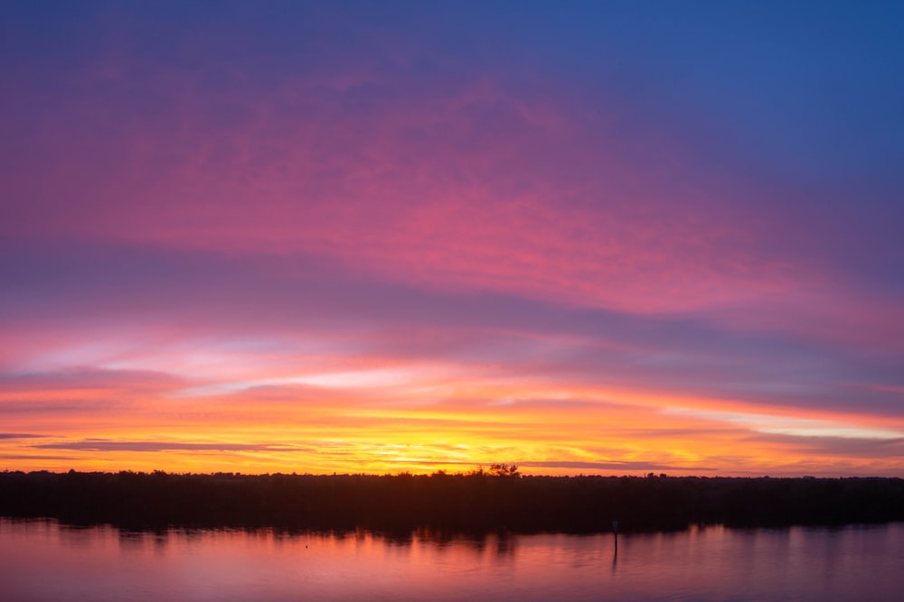 a sunset over a lake with a boat in the water