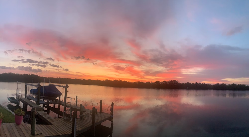 Un muelle en un lago con un barco al atardecer