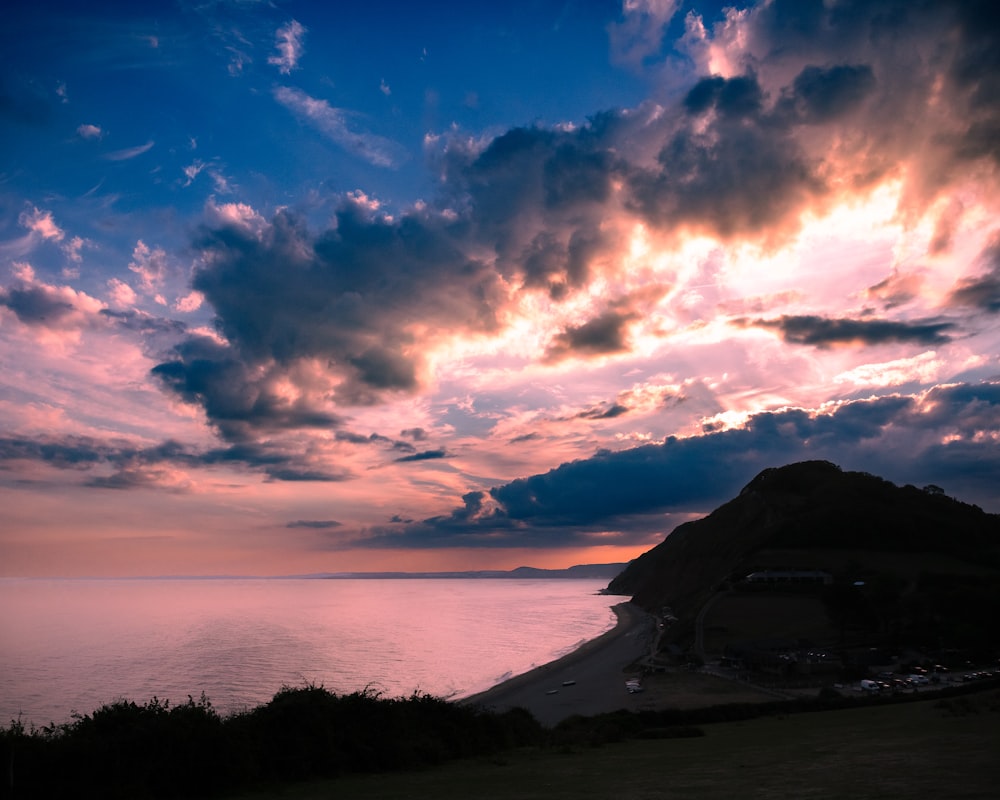 the sun is setting over the ocean with clouds in the sky