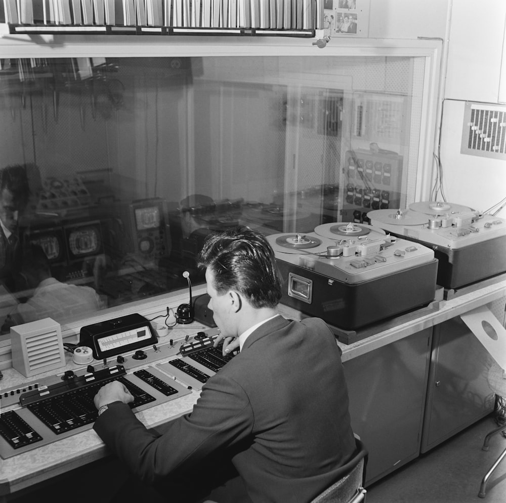 a man in a suit sitting at a desk in front of a radio