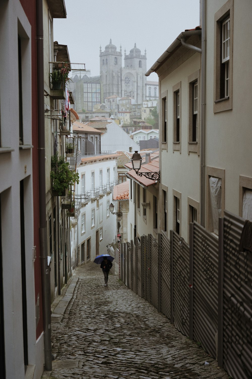 a person walking down a cobblestone street holding an umbrella