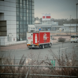 Smiling team members loading Coca-Cola products into delivery trucks at a modern warehouse.