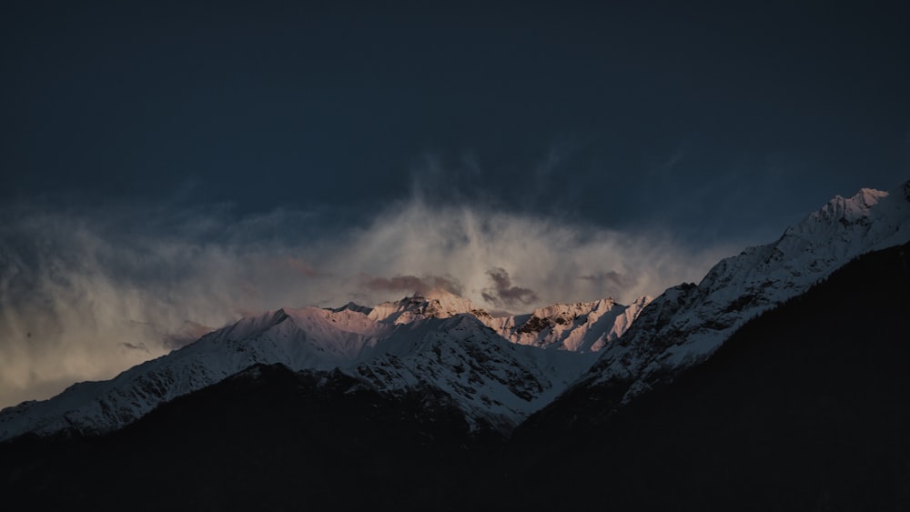 a mountain covered in snow under a cloudy sky