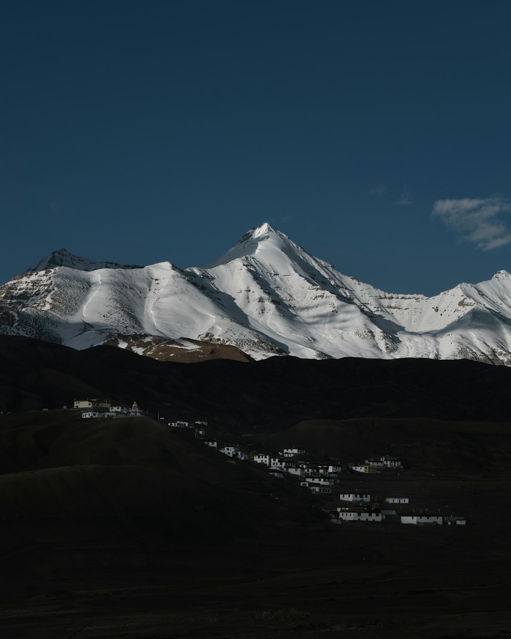 a snow covered mountain range with houses in the foreground