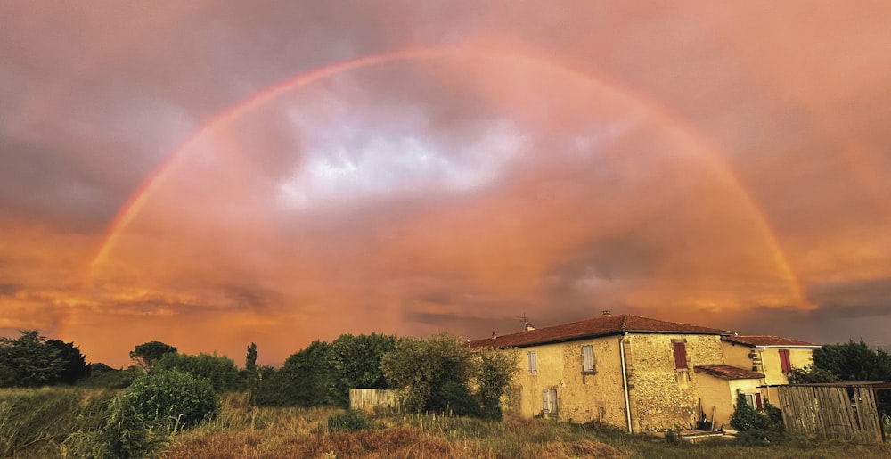 Um arco-íris duplo aparece sobre uma casa em um campo