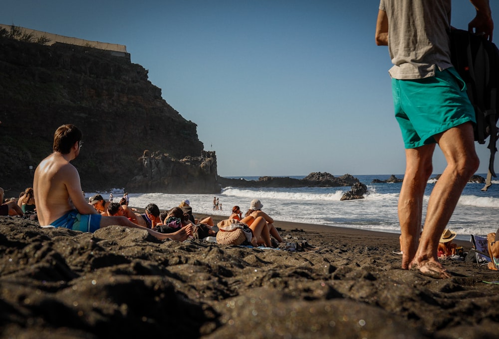 a group of people sitting on top of a sandy beach