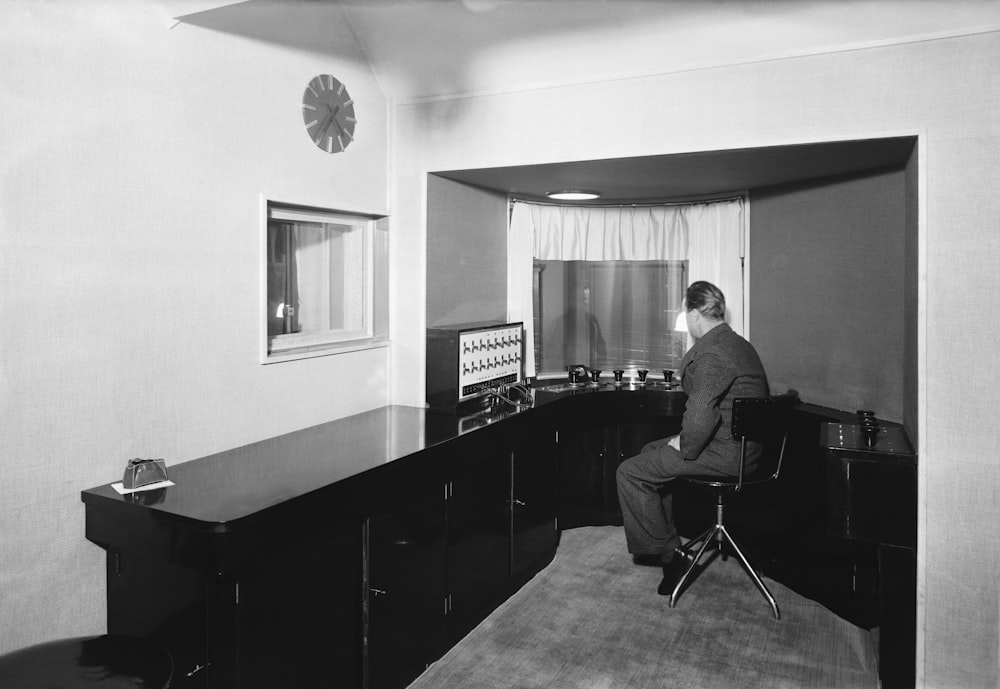 Una foto en blanco y negro de un hombre sentado en un escritorio