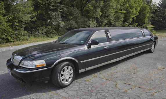 Sleek black limousine waiting outside LaGuardia Airport terminal with driver holding a welcome sign.