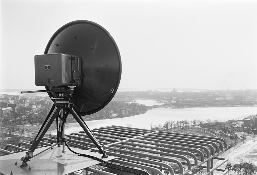 a black and white photo of a satellite dish on a tripod