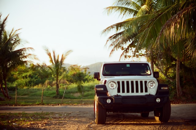 A rugged jeep driving through lush green rice terraces in Sidemen, Bali during sunset.