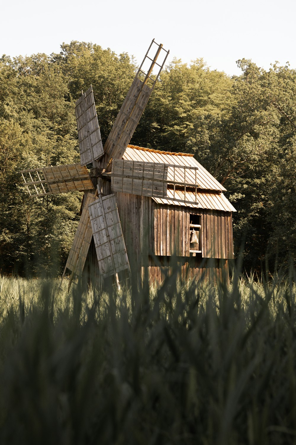 an old wooden windmill in a field with trees in the background