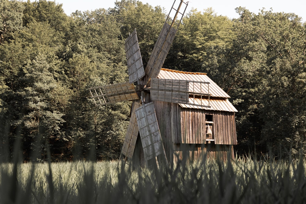 an old wooden windmill in a field with trees in the background