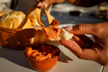 Hands spreading chimi gel over a warm slice of crusty bread, steam rising gently
