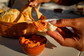 Artisan spreading golden apricot jam on a slice of crusty bread with natural light highlighting the texture