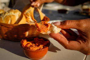 Hands spreading chimi gel over a warm slice of crusty bread, steam rising gently