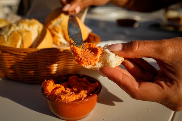 Artisan spreading golden apricot jam on a slice of crusty bread with natural light highlighting the texture
