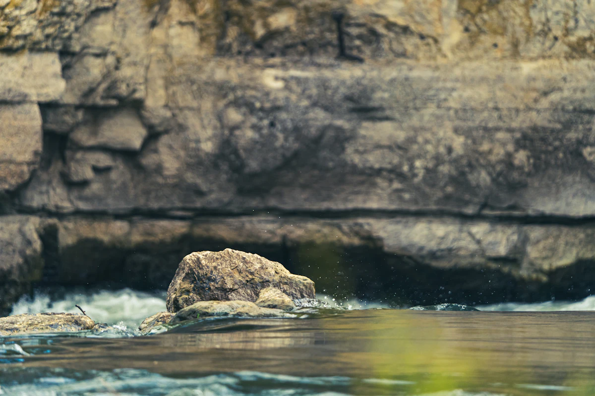 Clear green river running past a rocky bluff lined with trees