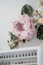 A cozy nail salon corner with soft green plants and pastel pink accents.