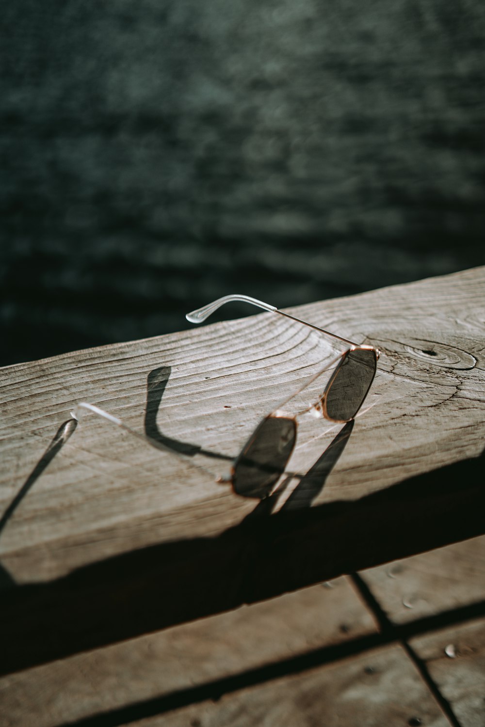 a pair of sunglasses sitting on top of a wooden dock