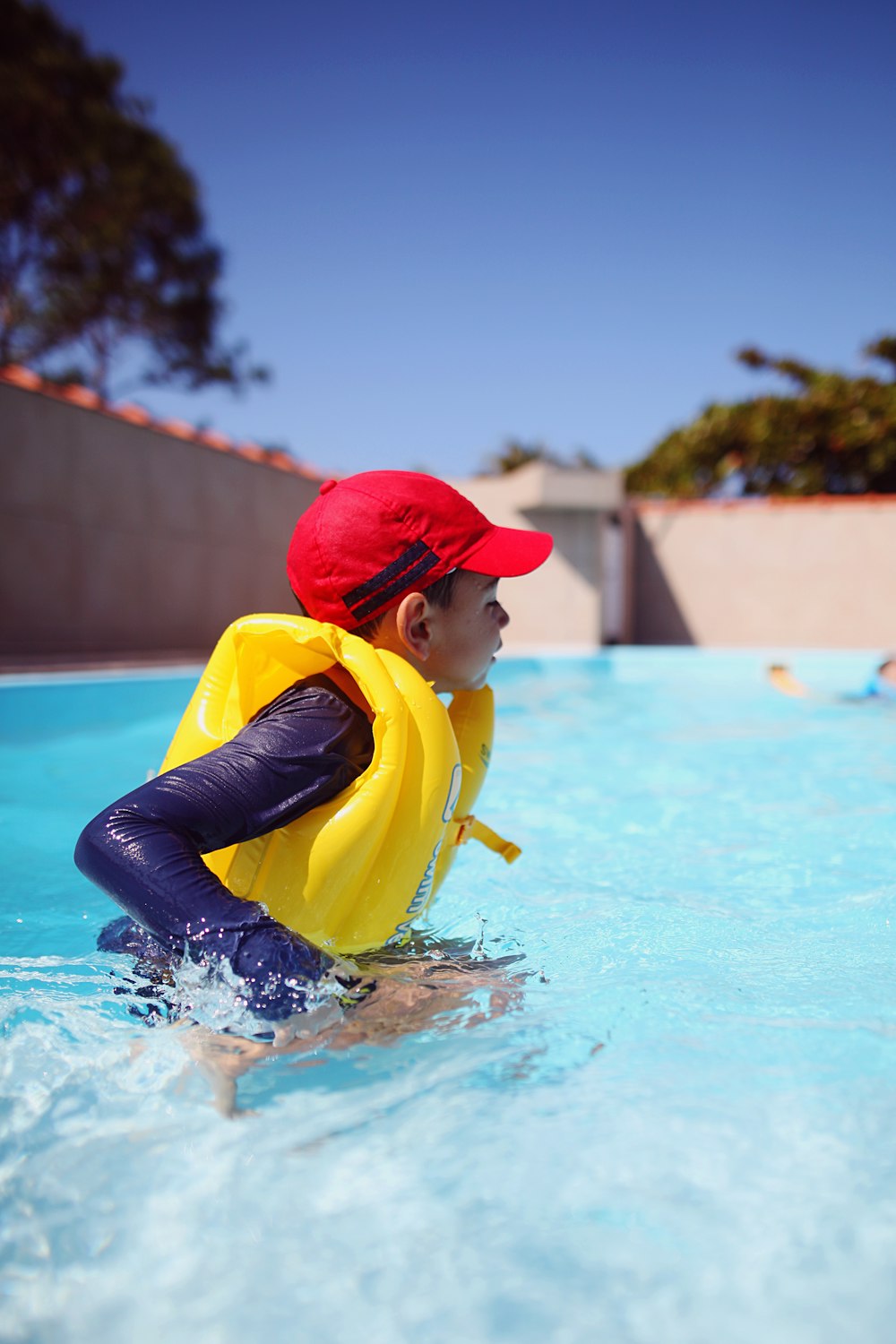 a boy in a yellow life jacket in a swimming pool