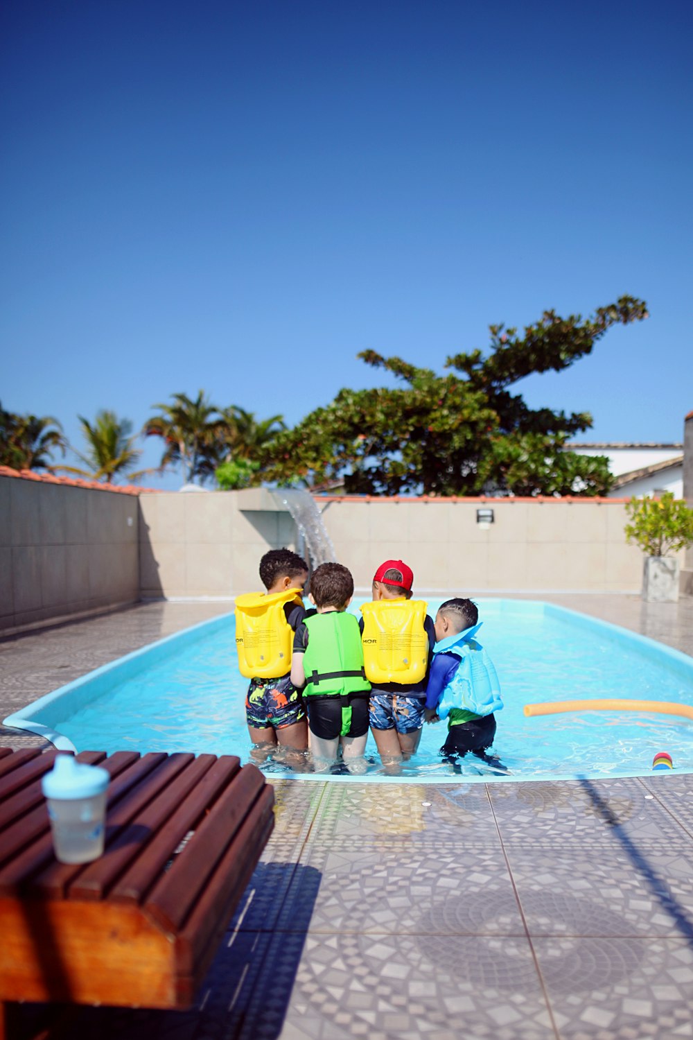 a group of young boys standing next to a swimming pool