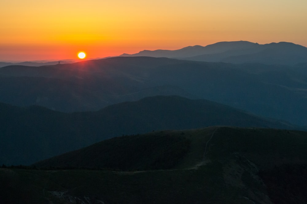 the sun is setting over a mountain range