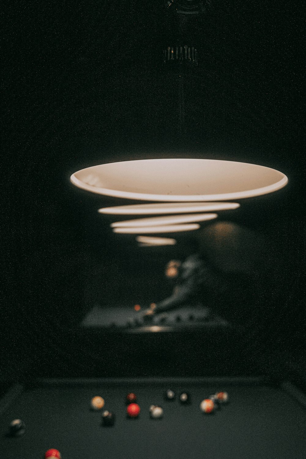 a pool table in a dark room with a light hanging from the ceiling