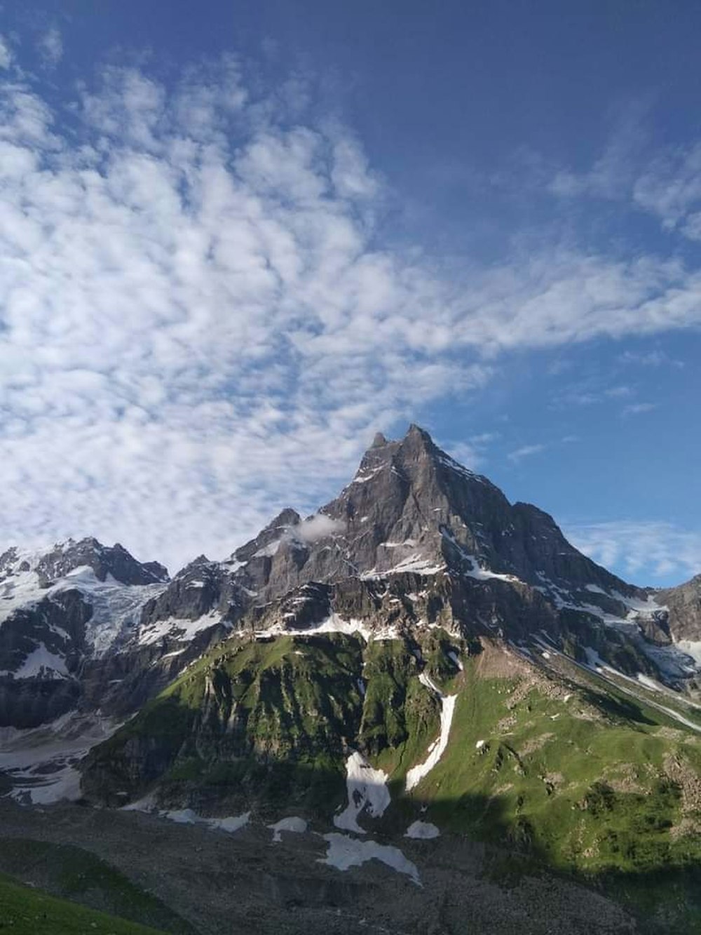 a very tall mountain covered in snow under a blue sky