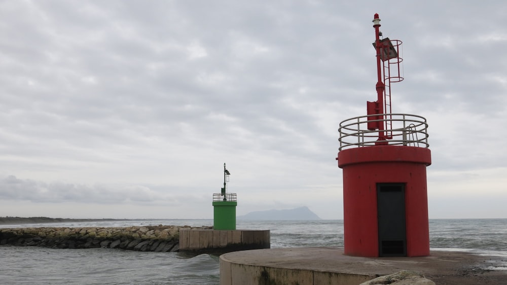 a red tower sitting on top of a pier next to the ocean