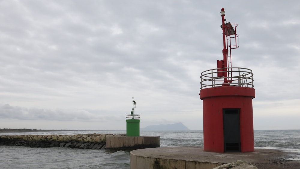 Una torre rossa seduta sulla cima di un molo vicino all'oceano