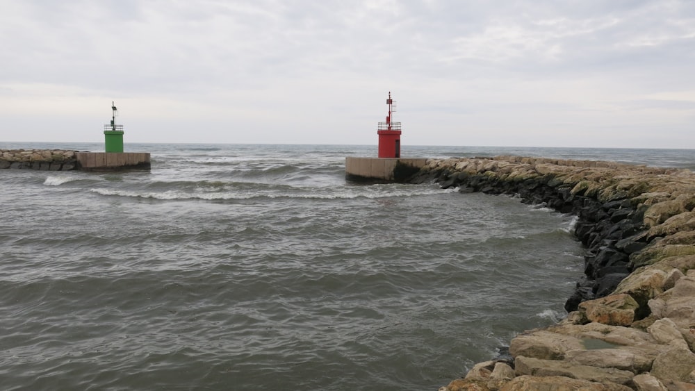 a couple of red and green lighthouses sitting on top of a rock wall