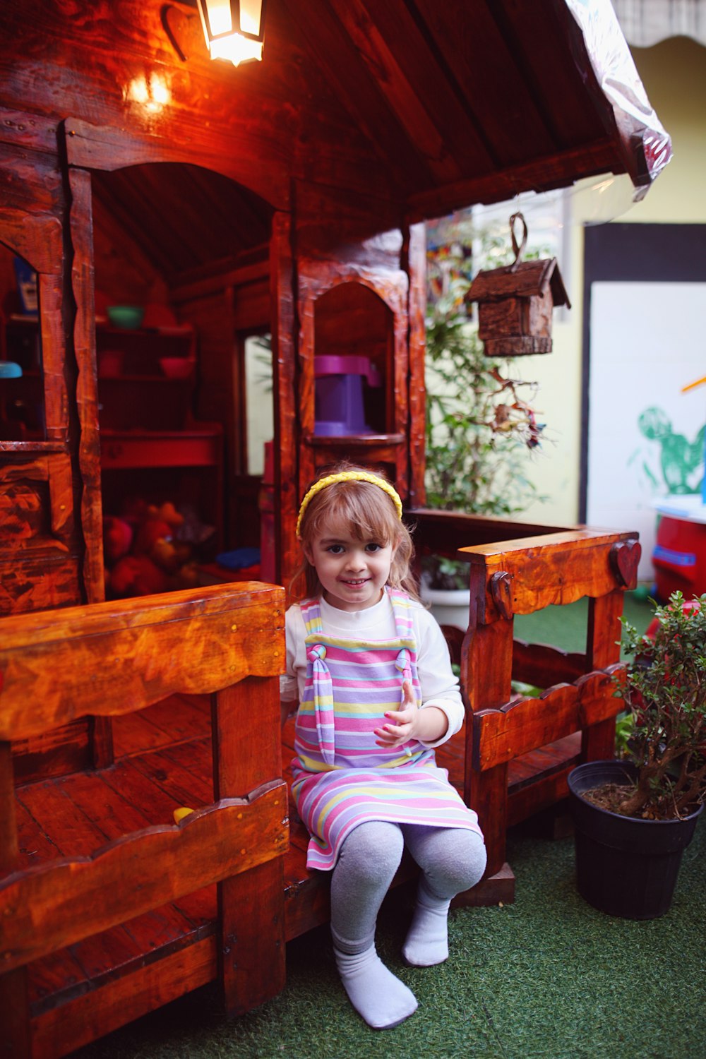 a little girl sitting on a wooden bench