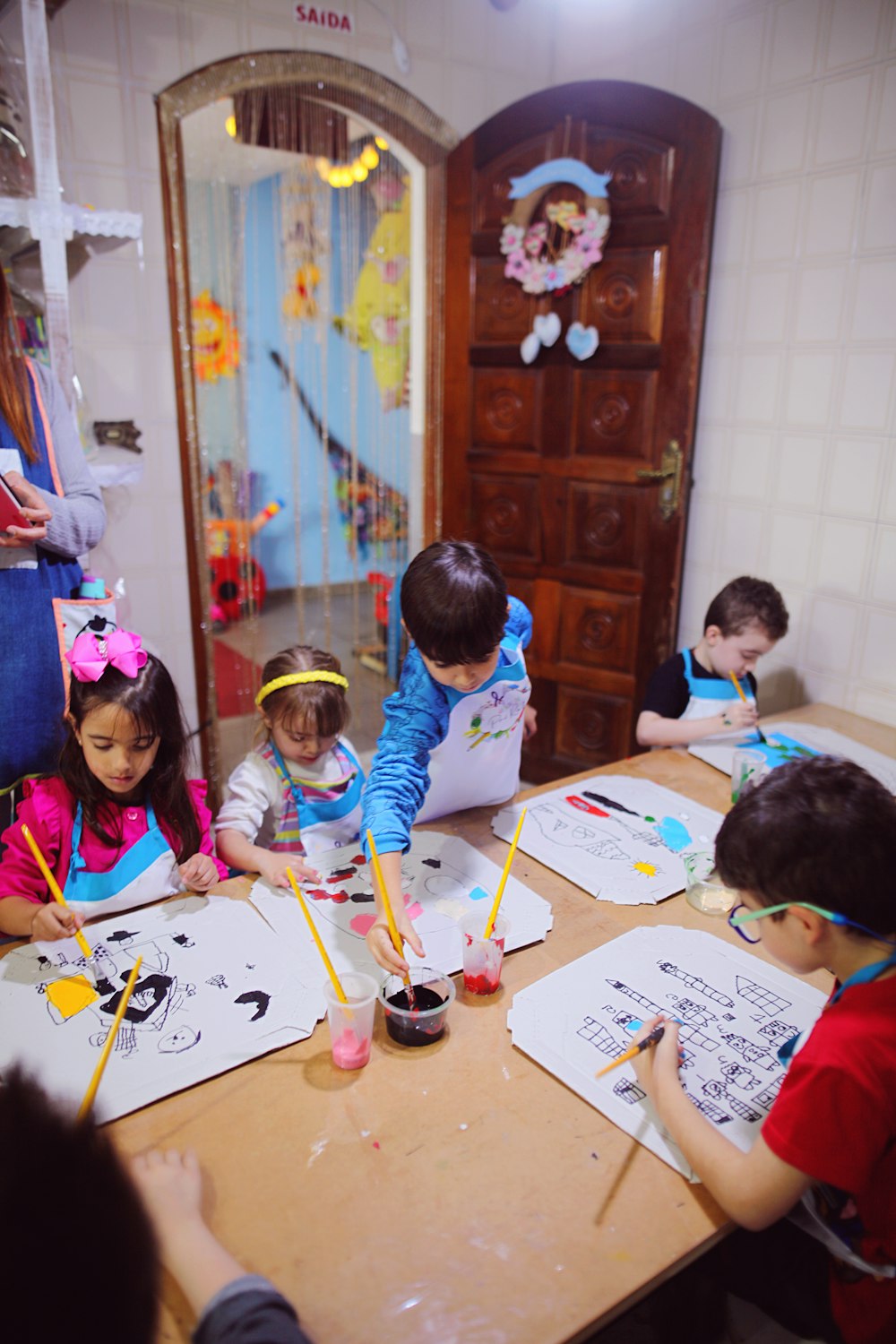 a group of children sitting at a table doing crafts