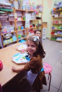 a little girl sitting at a table in a store