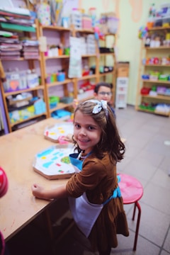a little girl sitting at a table in a store