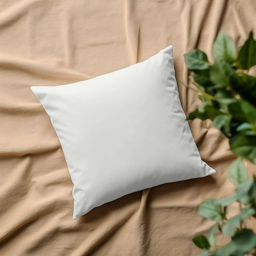 ein weißes Kissen, das auf einem Bett neben einer Pflanze sitzt