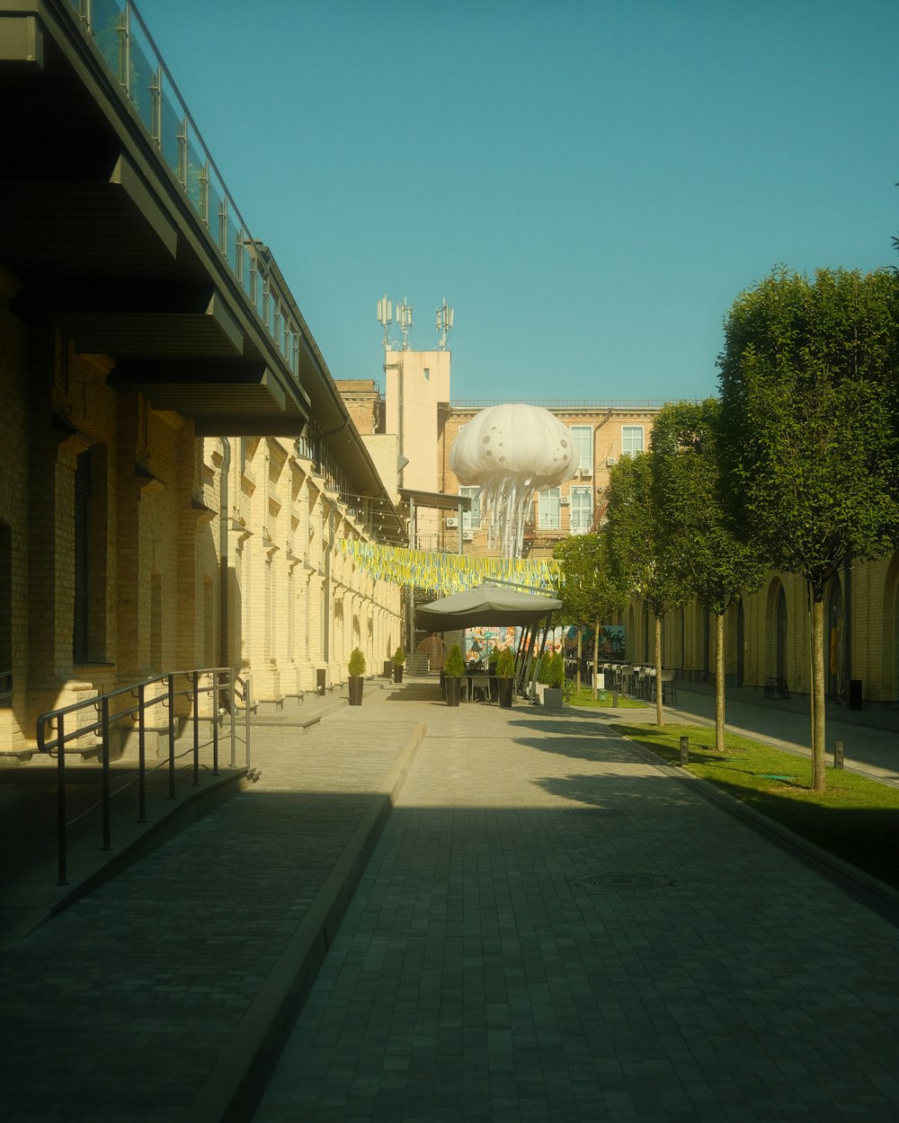 a walkway between two buildings with a large elephant statue in the background