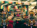 An indoor amusement area featuring colorful decorations with cartoonish designs. There are large robot-like figures positioned prominently alongside vibrant ride-on cars for children. Various colorful designs cover the walls and ceilings, reflecting a playful and fantasy-themed setting.