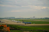 A panoramic view of an airport runway with planes lined up and ready.