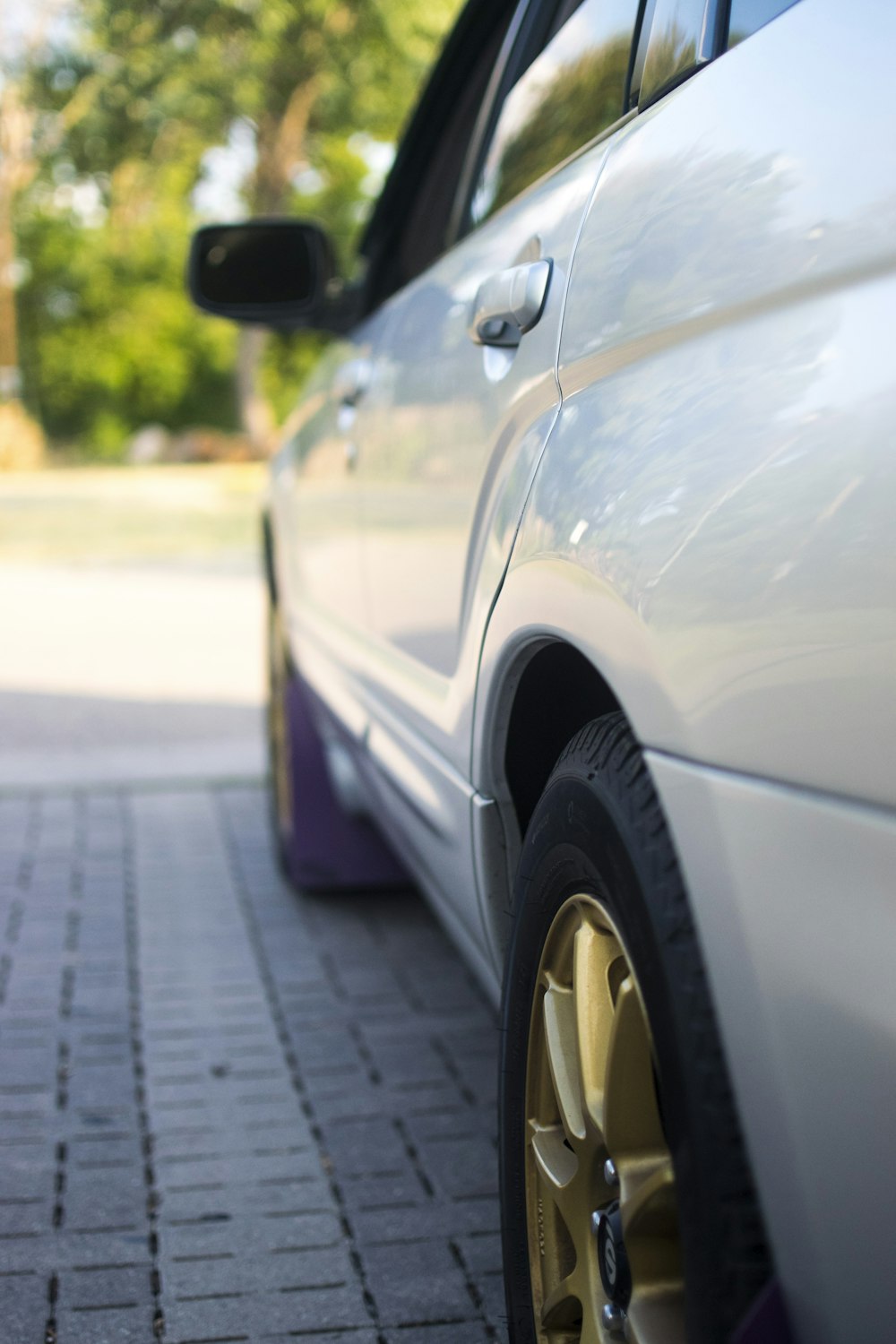 a close up of a white car parked on a brick road