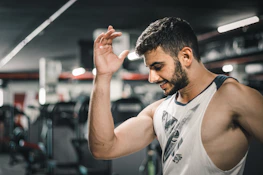 A smiling professional in workout gear showing off toned arms in a Manhattan park.