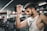A fit older man smiling while lifting weights in a gym setting.